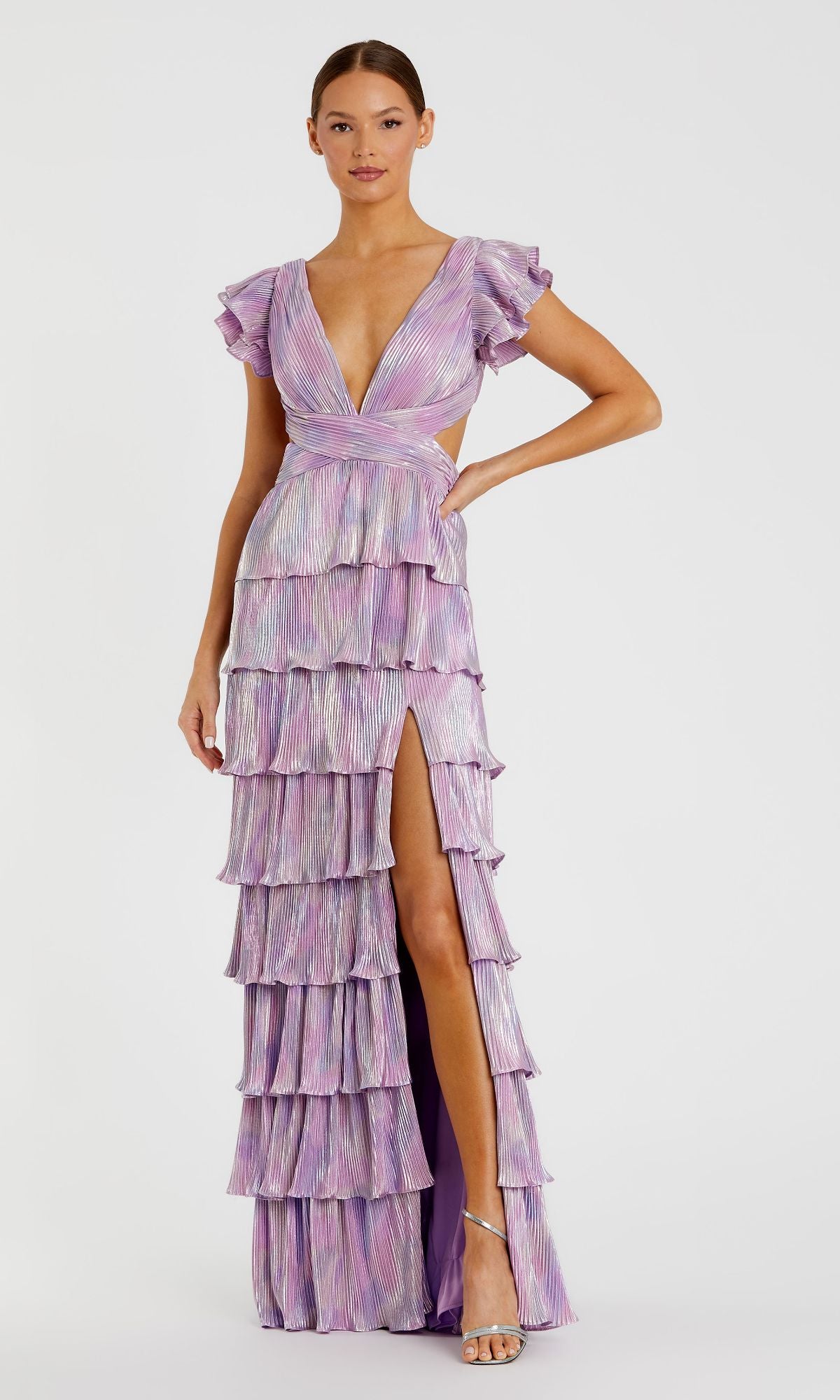 A woman models the Mac Duggal Open-Back Tiered Formal Dress 26740 in lavender, featuring a v-neck, flutter sleeves, tiered ruffles, cutout sides, a high slit, and a lace-up open back against a plain background.